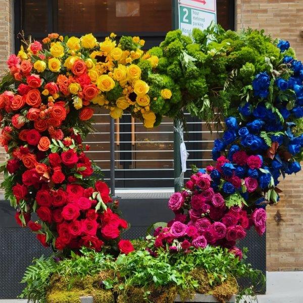 Pride bouquet in a heart made of rainbow colored flowers