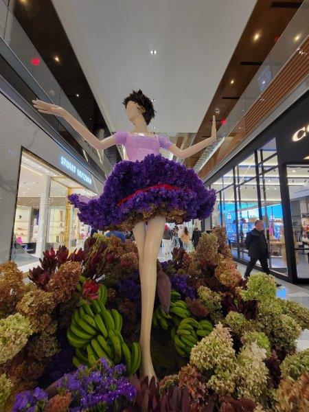 Chita Rivera floral mannequin striking a pose in green and purple foliage 