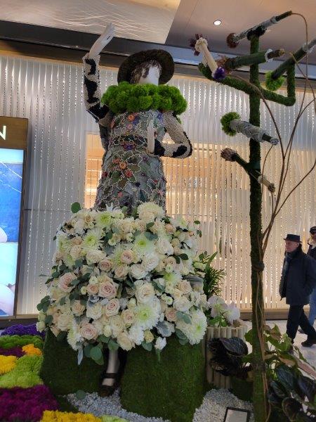 Bella Azbug floral mannequin in a green and white floral gown with microphones