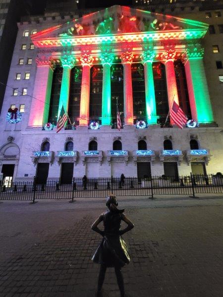 New York Stock Exchange lit up for the holidays, with the Fearless Girl in the foreground