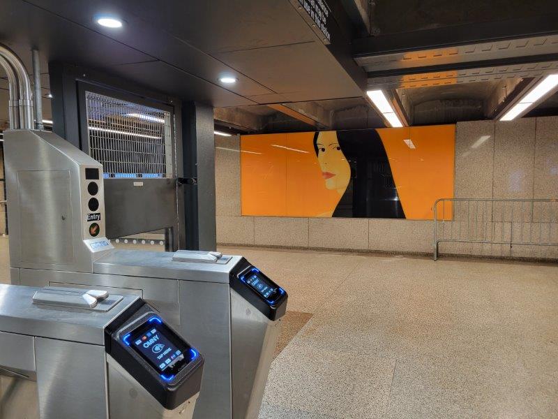 OMNY subway turnstile with art by Alex Katz in the background at the 57th and 6th sunway station