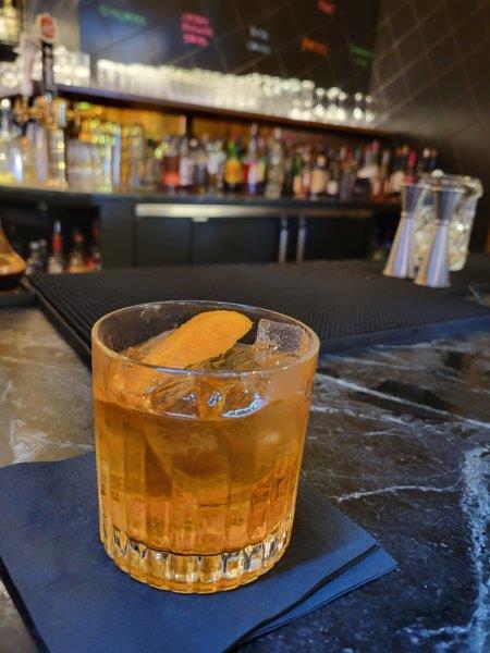 Manhattan vs. Old Fashioned - Classic old fashioned cocktail garnished with an orange peel