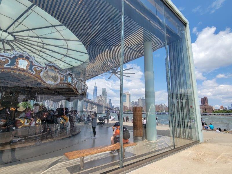 Glass pavilion of Jane's Carousel with a backdrop of the Manhattan skyline