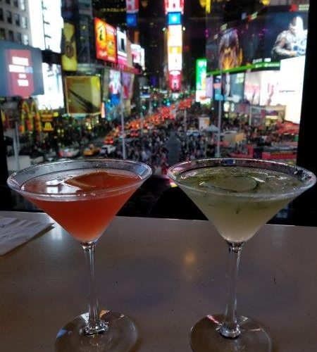 Drinks in martini glasses with a backdrop of Times Square