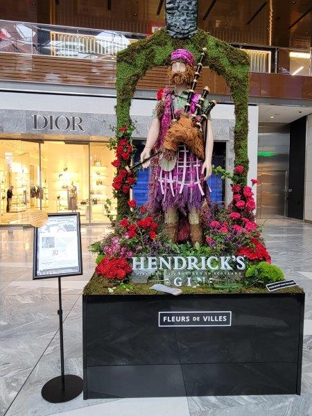 Scottish Bagpiper in a traditional outfit made of flowers with bagpipes