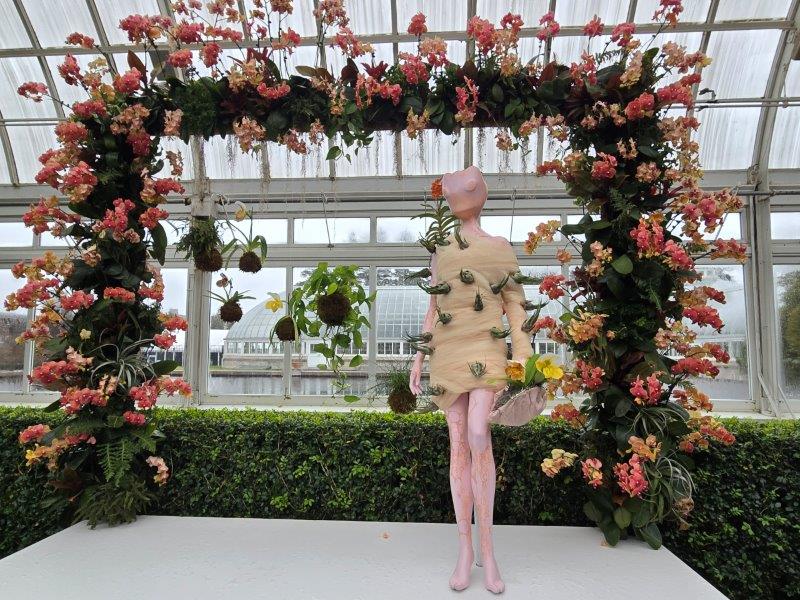 Animal mannequin on a platform wearing a peach orchid dress with a peach orchid frame as a backdrop 