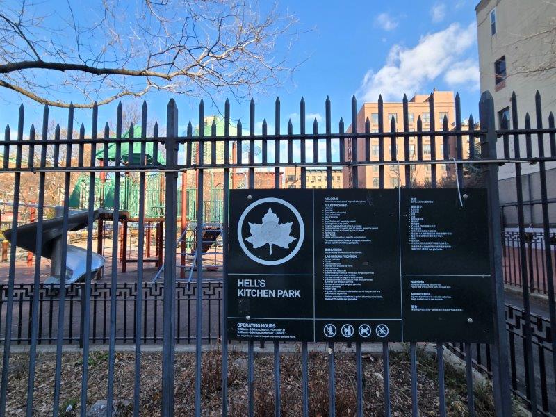 Sign for Hell's Kitchen Park with a children's playground at the back